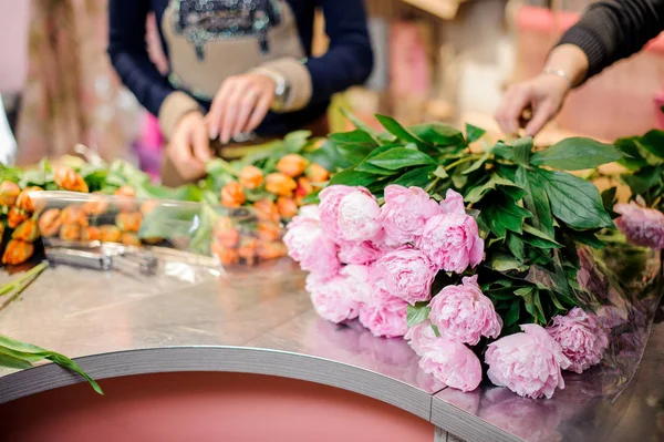 Floristas fazendo buquês de peônias cor de rosa e tulipa laranja — Fotografia de Stock