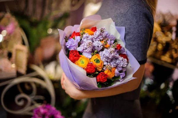 Niña sosteniendo un ramo de ranúnculos amarillos, lilas violetas y tulipanes rojos —  Fotos de Stock