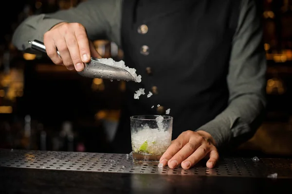 Barman ajoutant une glace dans le verre avec un sucre de canne et de la chaux — Photo