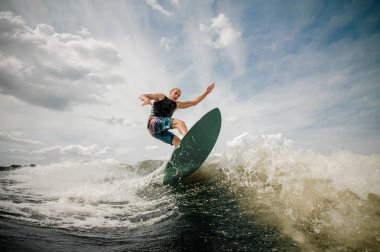 Atletik erkek wakesurfing bulutlu gökyüzü karşı yönetim kurulu
