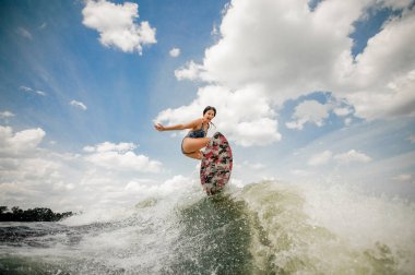 Sexy young woman having fun wakesurfing anf jumping on the board clipart