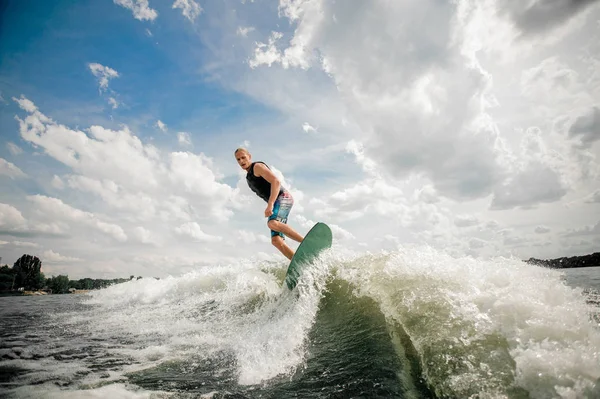 Tall man wakesurfing on the board down the river against the sky — Stock Photo, Image