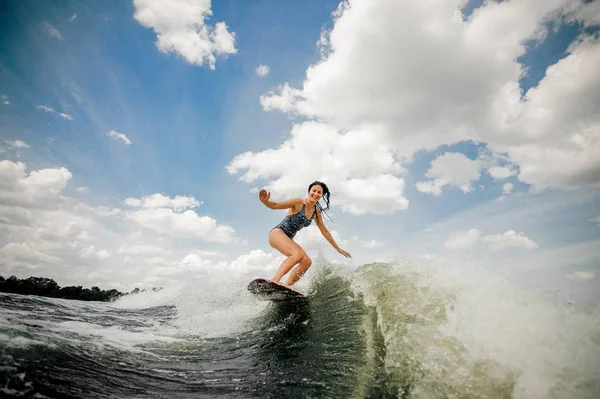 Karcsú mosolygó nő wakesurfing a fedélzeten, az ég ellen — Stock Fotó