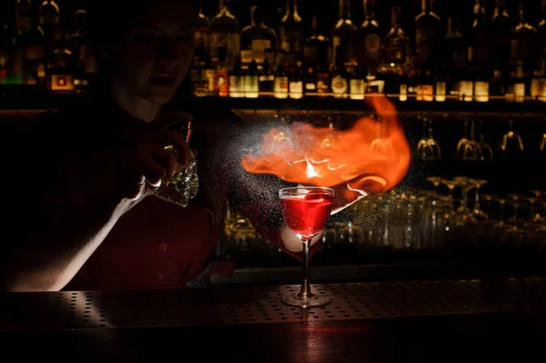 Vrouwelijke bartender spuiten op de brand wedstrijd boven de cocktail o — Stockfoto