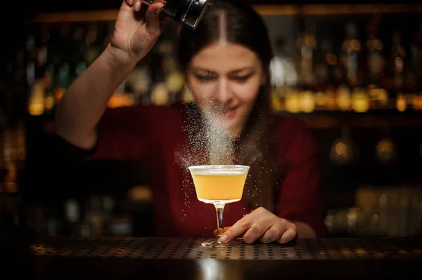 Smiling female bartender pouring a spice to the delicious cockta