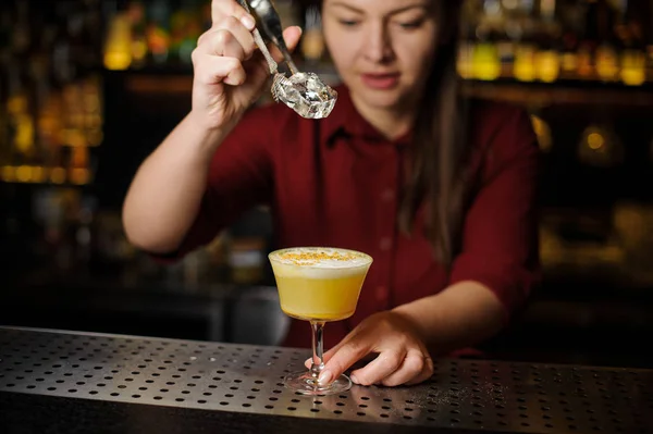 Kobiece barman dodanie lodu do koktajlu żółty — Zdjęcie stockowe