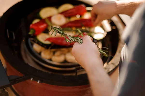 Homem mãos cozinhar legumes na grelha e adicionar alecrim em um prato — Fotografia de Stock