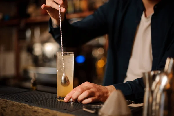 Barman mano revolviendo un cóctel de verano de color naranja fresco y dulce — Foto de Stock