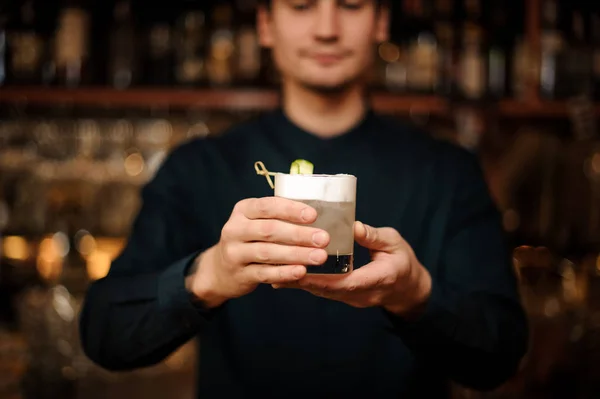 Unga bartendern håller ett glas fyllt med — Stockfoto