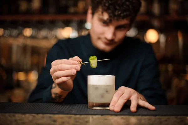 Bartender dekorera ett cocktailglas med en gurka på en trä spett — Stockfoto