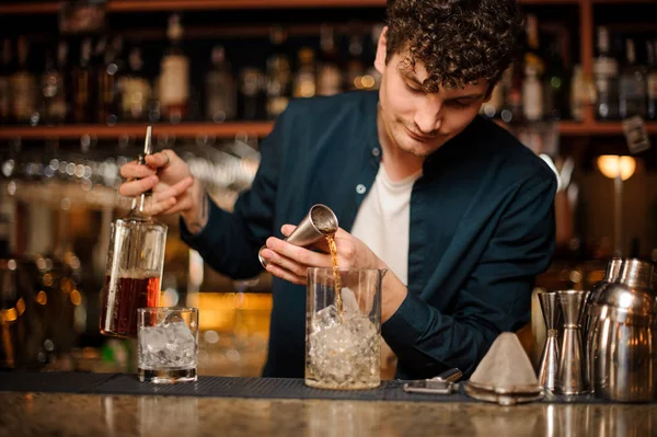 Cantinero Brunet añadiendo una bebida alcohólica en el vaso con hielo — Foto de Stock