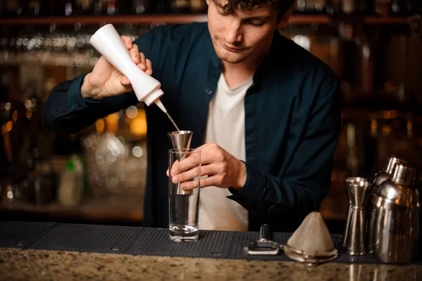 Μελαχροινός μπάρμαν που ρίχνει ένα οινοπνευματώδες ποτό στο τη μεζούρα — Φωτογραφία Αρχείου