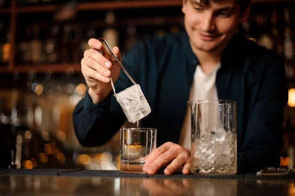 Cantinero poniendo un cubo de hielo grande en un vaso vacío — Foto de Stock