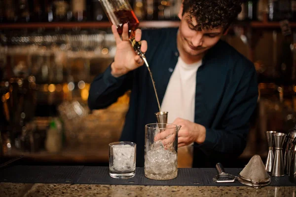 BRUNET bartendern hälla en alkoholhaltig dryck i en mätglaset — Stockfoto