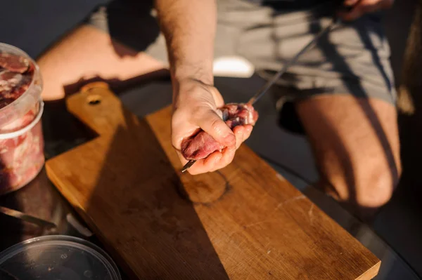 Человек нанизывает большие куски мяса на шампур — стоковое фото