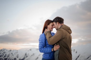 nazikçe birbirinize sarılın kar Dağları arka plan üzerinde kız ve bir adam