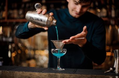 Barmen alkol kokteyl Blue Lagoon hazırlar