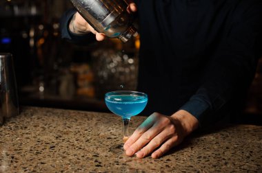 Barmen alkollü kokteyl Blue Lagoon shaker dan son damla içki alıyor.