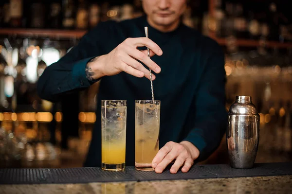 Bartender förbereder två alkoholhaltiga drinkar, omrörning ingredienserna — Stockfoto