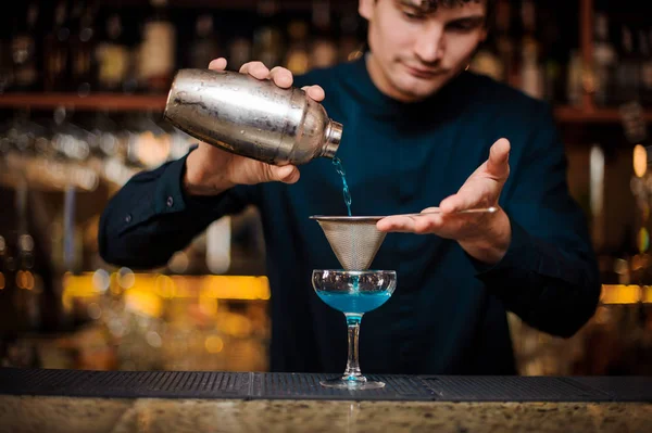 Barman en chemise bleue filtre un cocktail alcool Blue Lagoon — Photo