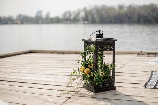 IJzeren lantaarn ingericht met tropische bloemen als het decor van een bruiloft op de rivieroever — Stockfoto