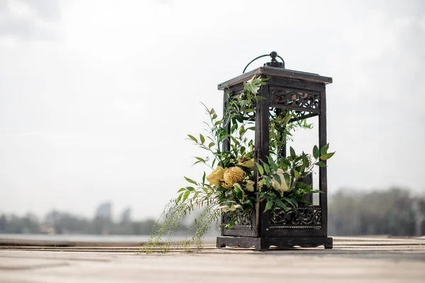Tutup lentera besi dihiasi dengan bunga tropis sebagai dekorasi pernikahan di tepi sungai — Stok Foto