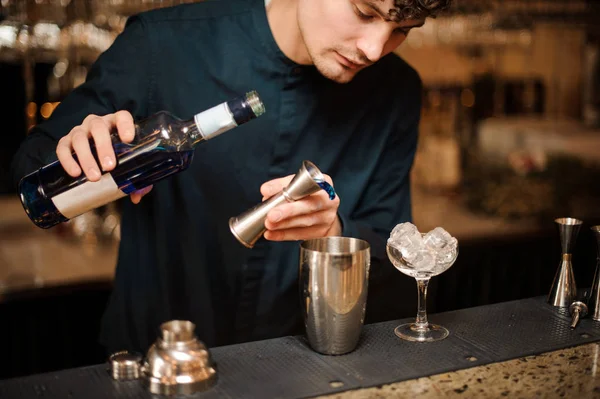Unga bartendern hälla blå sprit i en shaker för att göra en fräsch sommar cocktail — Stockfoto
