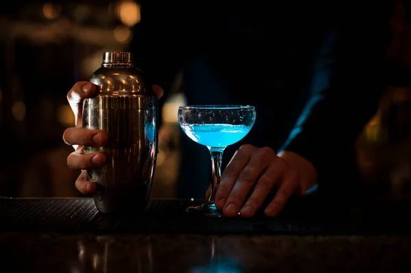 Manos de hombre sosteniendo un vaso con cóctel azul de verano y botella — Foto de Stock