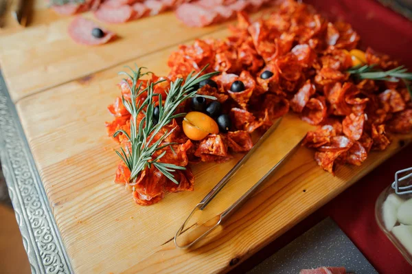 Wurst tagliato sul piatto di legno decorato con olive, pomodori e rosmarino — Foto Stock