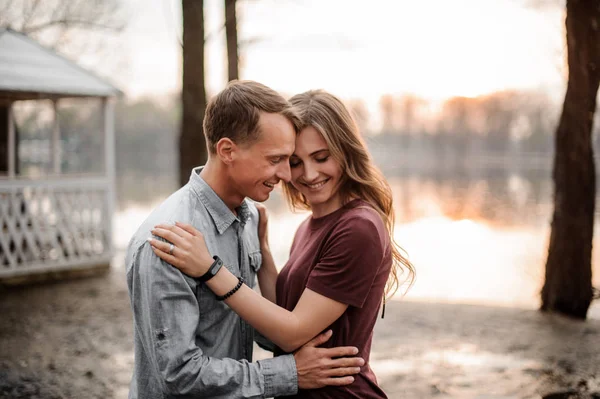 Verliebtes Paar hält sich auf dem Hintergrund des Sees eng aneinander — Stockfoto