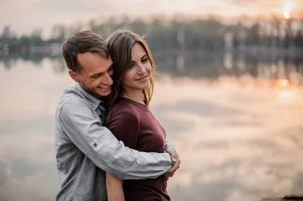 Uomo che abbraccia da dietro la sua donna sullo sfondo del lago — Foto Stock