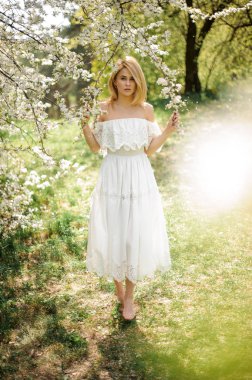 Kız beyaz ağaç yalınayak dalları altında ayakta