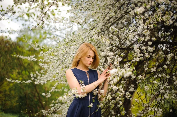Молода дівчина стоїть між гілками білого квітучого дерева — стокове фото