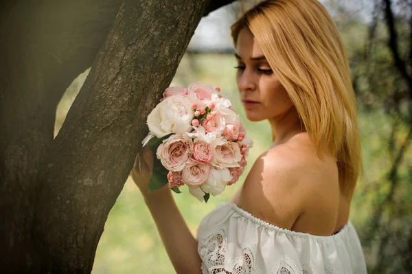 Chica de pie cerca del árbol con un ramo de color rosa — Foto de Stock