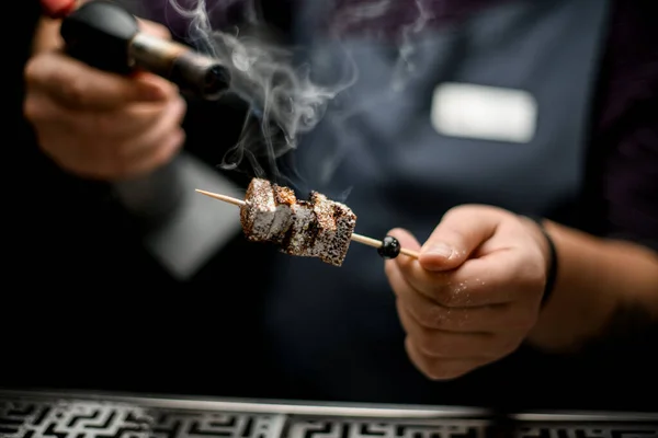 Professionele barman toasing een brownie stukken op de spies met een brander — Stockfoto