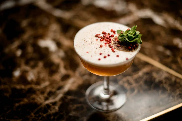 Cocktail nel bicchiere decorato con un ramo di foglia di menta, grani di pepe rossi e fetta di arancia essiccata — Foto Stock