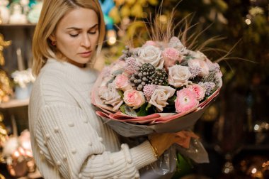 Elinde bir buket pembe ve bej renkli gül tutan bir kız tüylü ve kuru böğürtlenli.