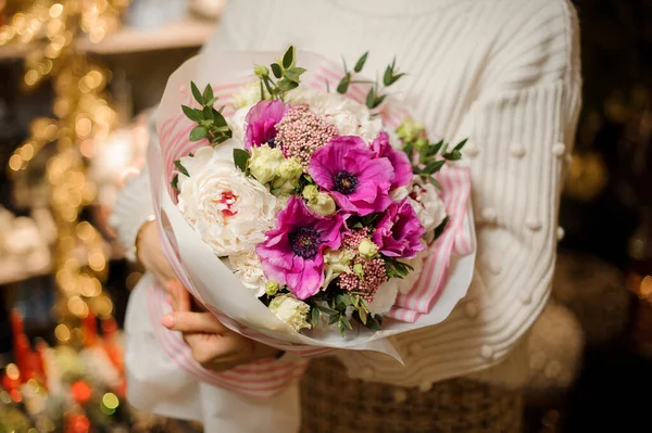 Дівчина тримає букет з фіолетовими рожевими та білими піоновидними трояндами, прикрашеними зеленим листям — стокове фото