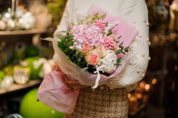 Elinde buket gül rengi çiçekler, yeşil yapraklar ve pembe koniler tutan bir kadın. — Stok fotoğraf