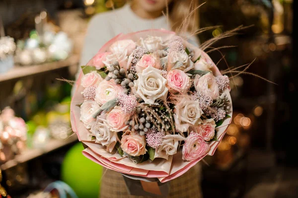 Mujer sosteniendo un ramo de rosas de color rosa y beige con una decoración de plumas y bayas secas —  Fotos de Stock