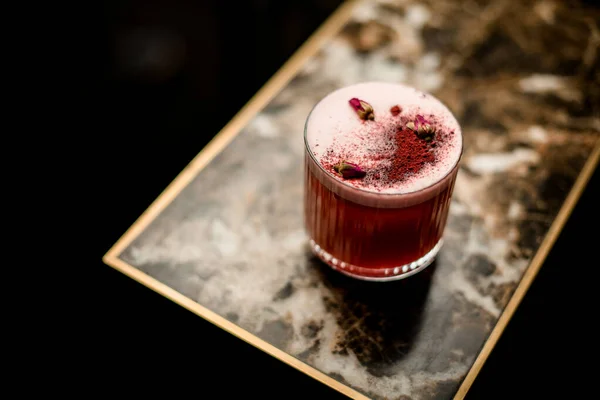 Αλκοολούχο κοκτέιλ με ένα απόβρασμα στο ποτήρι διακοσμημένο με μπαχαρικά και λίγο αποξηραμένο τριαντάφυλλο μπουμπούκια — Φωτογραφία Αρχείου