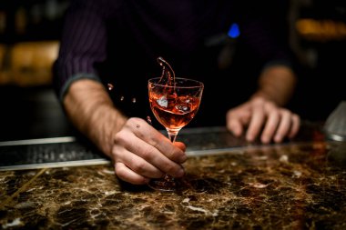 Profesyonel barmen küçük bardakta kokteyl servisi yapıyor. Karıştırıyor.