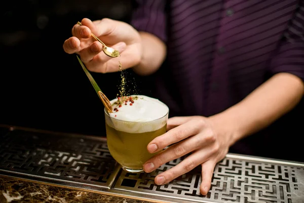 Barman voegt aan de cocktail versieren met een slagroom met een blad en gedroogde sinaasappel een pepererwt — Stockfoto