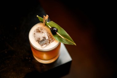 Yukarıdan yeşil tropikal yaprak ve kürdanın üzerinde siyah böğürtlen ile süslenmiş kremalı kokteyl içeceği görüntüsü