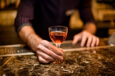 Küçük bardakta kısa bir kokteyl servisi yapan profesyonel bir barmen.