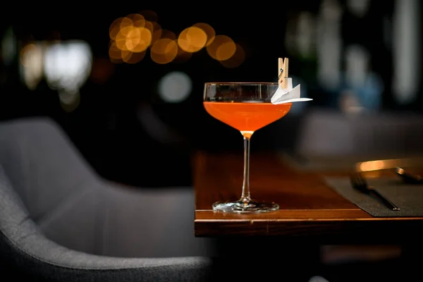 Orange cocktaildrink i glaset dekorerad med ett pappersflygplan i klädnypan — Stockfoto