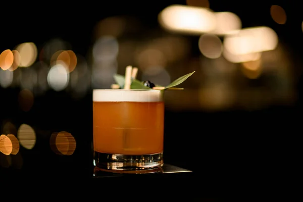 Köstliche Cocktailgetränk mit einem grünen tropischen Blatt und schwarzen Beeren auf dem Zahnstocher dekoriert — Stockfoto