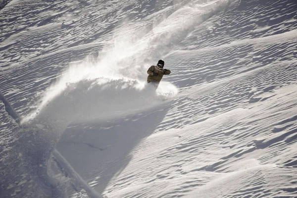 Snowboarder montando por la blanca colina cubierta de nieve —  Fotos de Stock