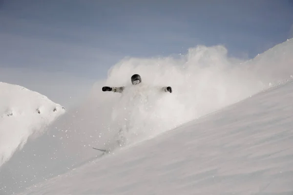 Snowboarder descendiendo por la colina cubierta de nieve haciendo un chapoteo blanco — Foto de Stock