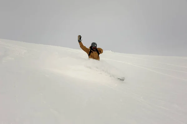 Paralimpiai snowboardos lovaglás a hóval borított dombon egyik kezét felfelé tartva — Stock Fotó